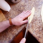 cut into (rough) diamond shaped strips, cut two slits (diagonally) in center of each.