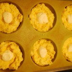 Place spoonful of cream cheese in well and top with batter.